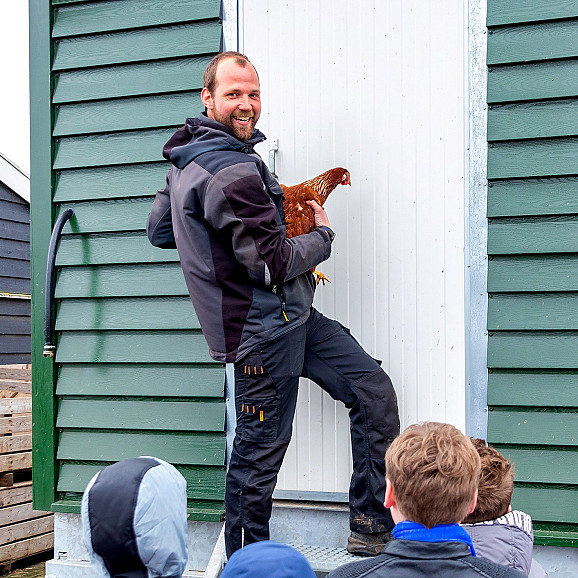 Man met kip geeft les aan kinderen